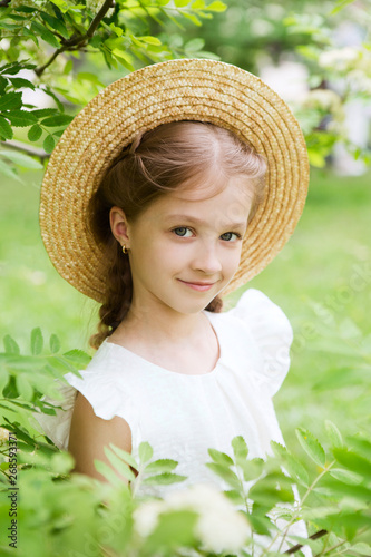  smiling little girl with hat in the blossoming garden
