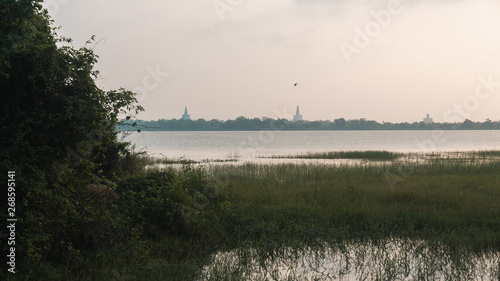 sunset over the lake with three pagodas in the background in Anuradhapura, Sri Lanka © CHAO