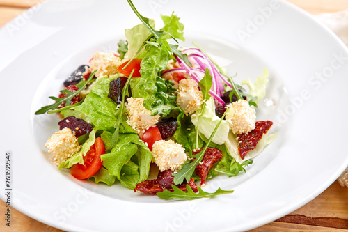 vegetarian salad with dried tomatoes and croutons on the wooden background
