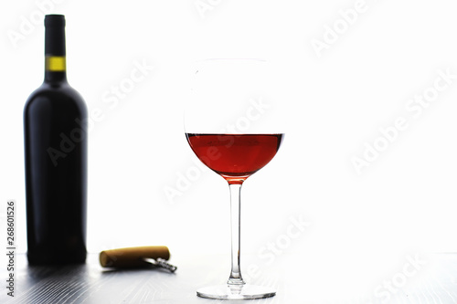 A glass of red dry wine on the table. Dark bottle and glass of wine.