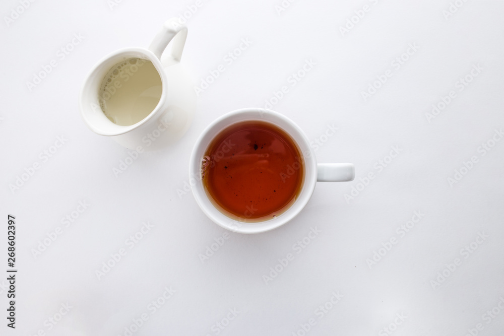 A cup of black tea with and milk jug isolated on white background top view - obrazy, fototapety, plakaty 