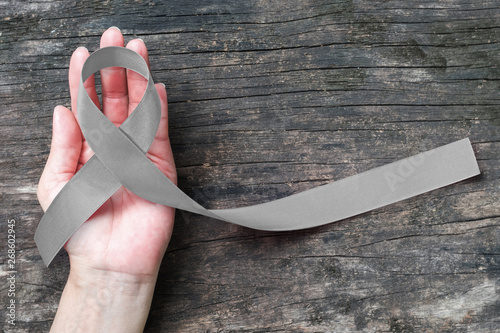 Brain cancer awareness with grey ribbon on helping hand (isolated with clipping path) symbolic bow color for Allergies, Alpha-1 Antitrypsin Deficiency, Aphasia, Asthma, Borderline Personality Disorder photo