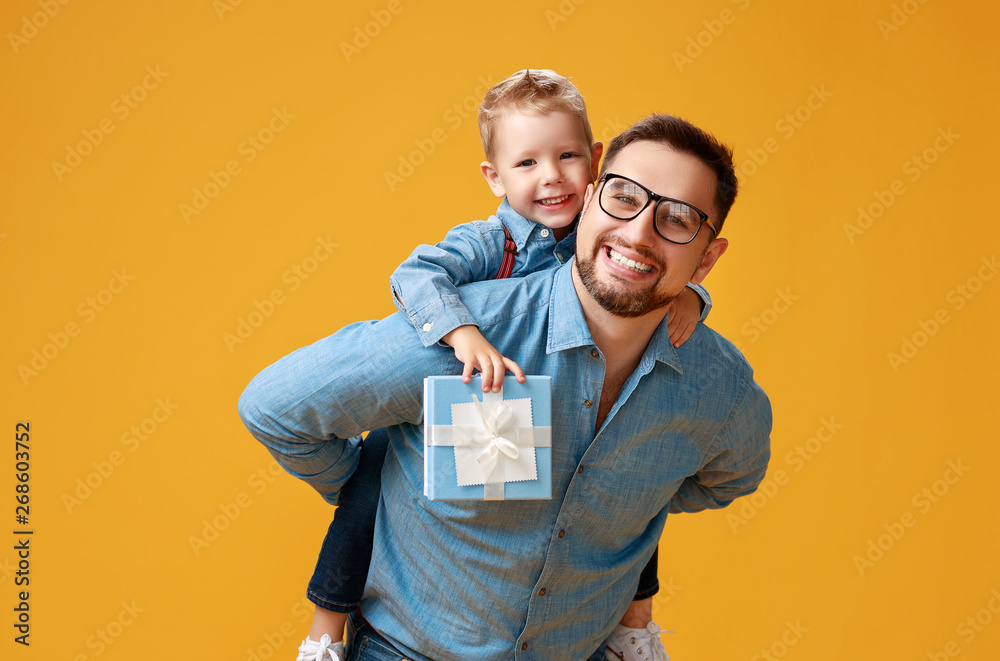 happy father's day! cute dad and son hugging on yellow background - obrazy, fototapety, plakaty 