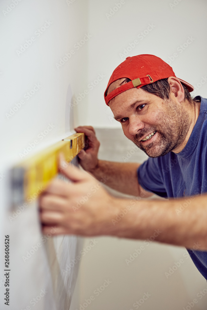 Worker using bubble level for walls and tiles inside the house - renovation fixes. Worker using bubble level for walls and tiles inside the house - renovation fixes.