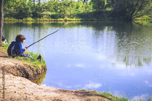 Child play fishing near lake. 