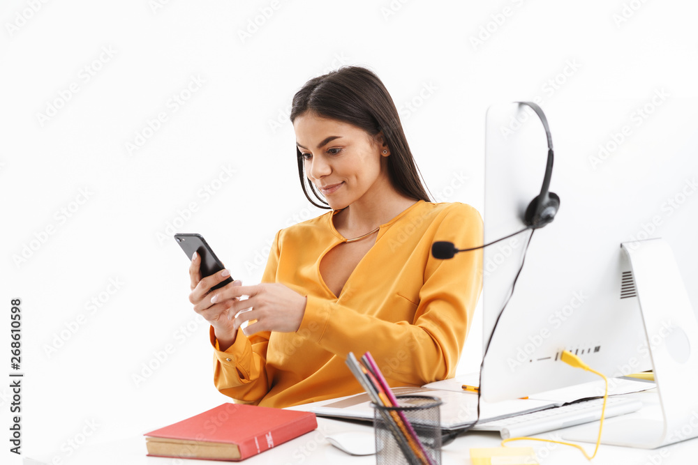 Portrait of pretty customer supporter woman holding smartphone while working in call center Portrait of pretty customer supporter woman holding smartphone while working in call center