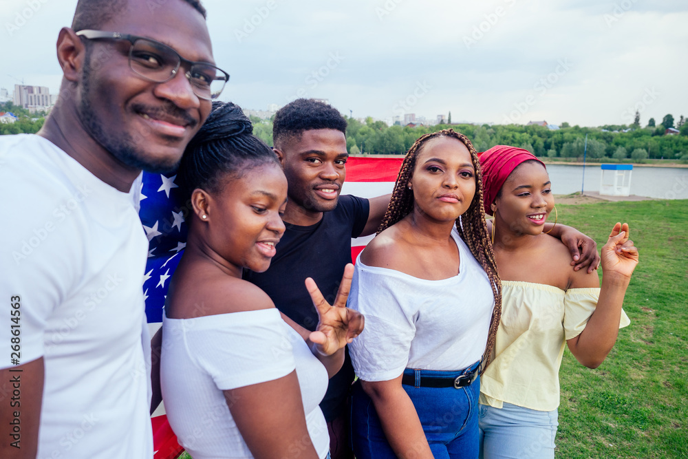 Group of girls and boys smiling with American flag in spring park autumn evening learning English language exchange students Group of girls and boys smiling with American flag in spring park autumn evening learning English language exchange students