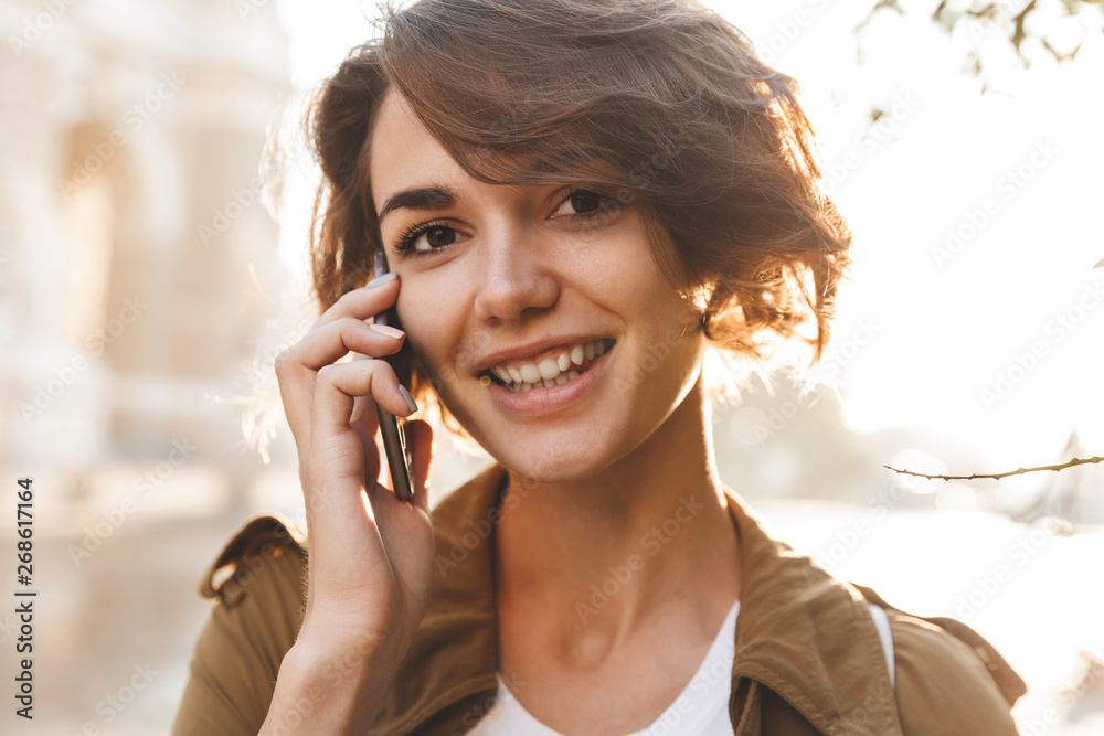Cute young amazing woman walking outdoors in park in beautiful spring day talking by mobile phone. Cute young amazing woman walking outdoors in park in beautiful spring day talking by mobile phone.