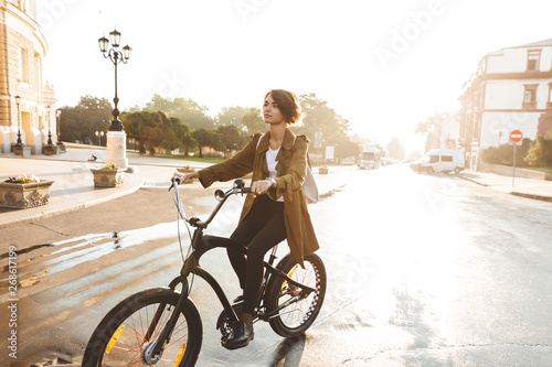 Cute young amazing woman walking outdoors in park with bicycle beautiful spring day.