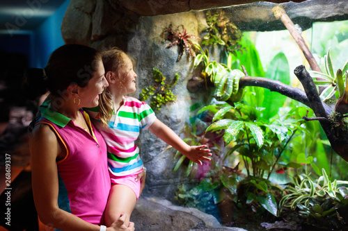 Foto Family watching snake in zoo terrarium.
