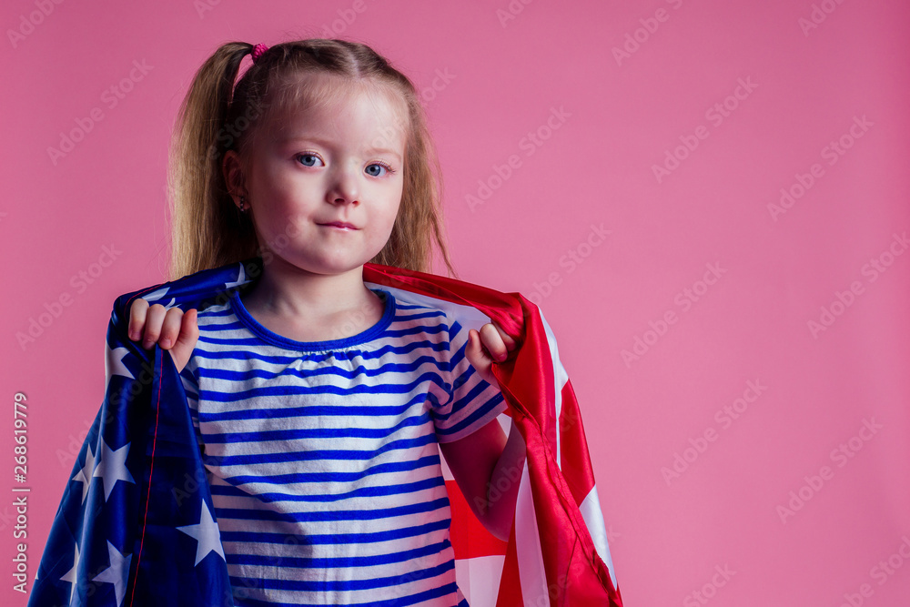 caucasian happy female baby in striped blue and white navy suit holding american flag in hand on a pink background in the studio.English language learning and freedom future profession army navy dream caucasian happy female baby in striped blue and white navy suit holding american flag in hand on a pink background in the studio.English language learning and freedom future profession army navy dream