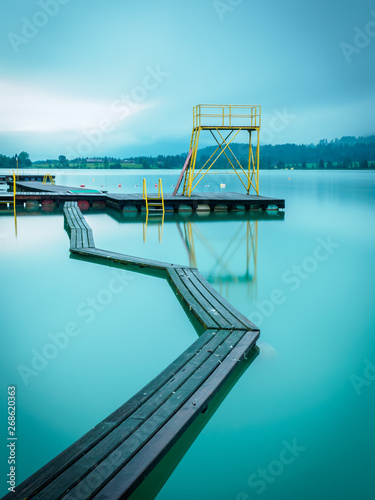 Morning at the lake in Walchsee with jetty and diving tower