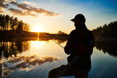 Fotografie sunset fishing. fisher with spinning rod