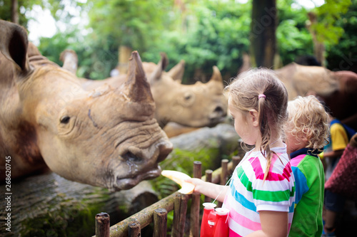 Kids feed rhino in zoo. Family at animal park. photo