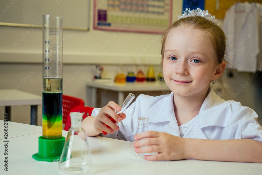 clever blonde school girl chemist in eyeglasses and white medical gown making science experiments chemistry ,mixing different chemical solutions in laboratory classroom clever blonde school girl chemist in eyeglasses and white medical gown making science experiments chemistry ,mixing different chemical solutions in laboratory classroom