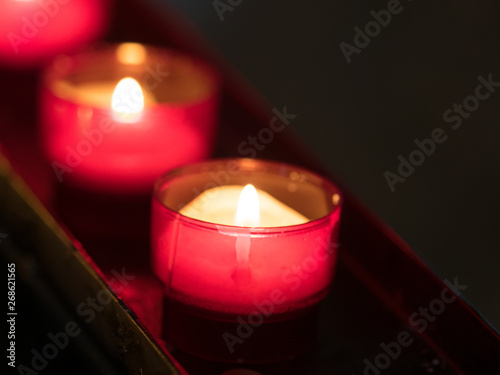 close up of a prayer candle lit in a red container