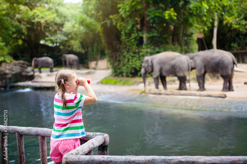 Photography Kids feed elephant in zoo. Family at animal park.