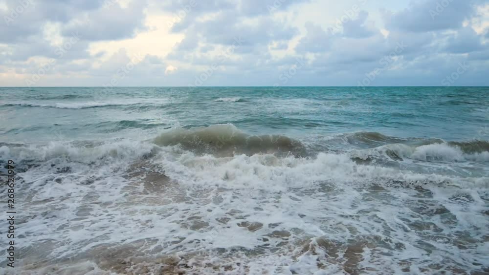 Large waves crashing onto a tropical beach at sunset Large waves crashing onto a tropical beach at sunset