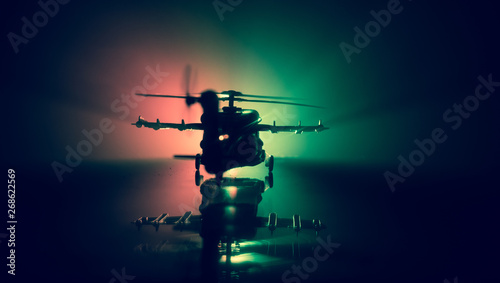 Fototapeta Naklejka Na Ścianę i Meble -  Silhouette of military helicopter ready to fly from conflict zone. Decorated night footage with helicopter starting in desert with foggy toned backlit. Selective focus.