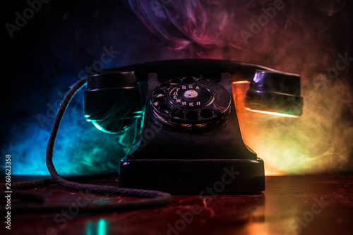 old black telephone on old wood plank with art dark background with fog and toned light. empty space
