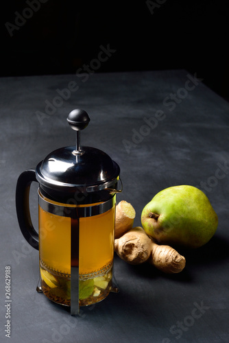 Teapot with ginger tea and pear on dark background. photo