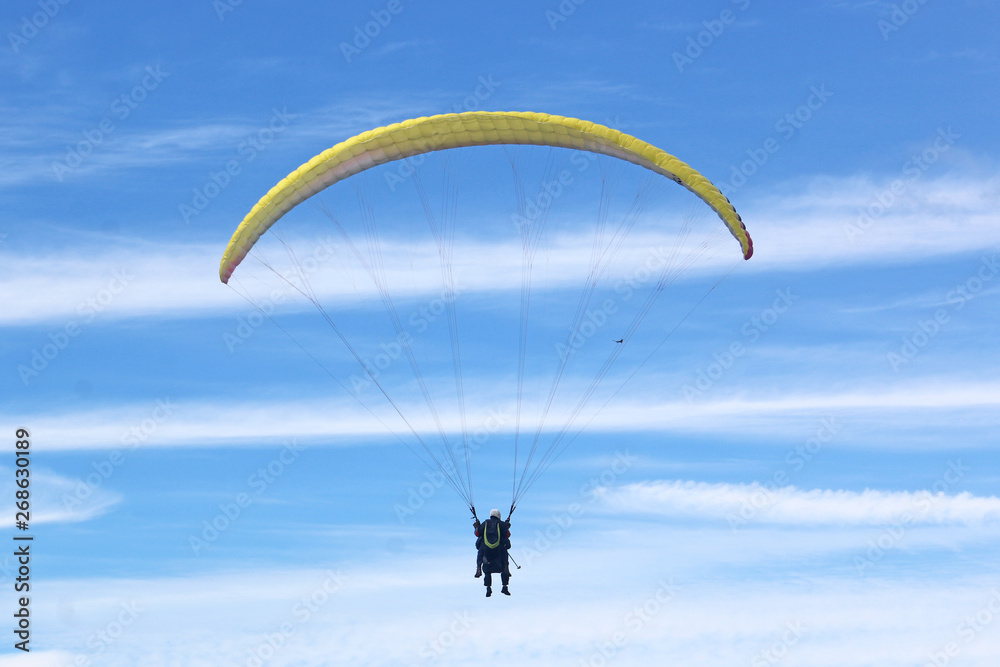 Tandem paraglider flying yellow wing Tandem paraglider flying yellow wing