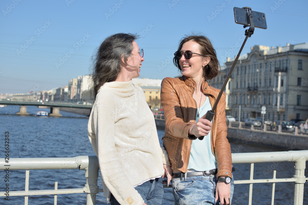 young ladies tourists in Saint Petersburg Russia take selfies on a wooden bridge in the historical city center