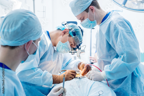 Spinal surgery. Group of surgeons in operating room with surgery equipment. Laminectomy