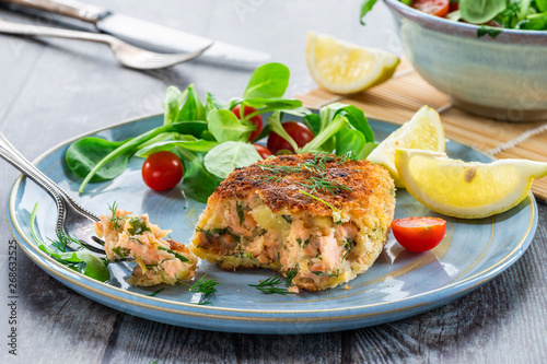 Homemade salmon fish cake with fresh leaf salad garnished with lemon