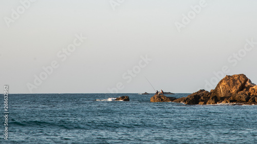 Fisherman fishing on a rock in ocean in Algeria