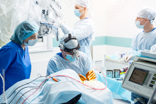 Brain surgery. Group of surgeons in operating room with surgery equipment.