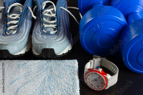 Sneakers, Dumbbells, a Towel and a Watch on a Dark Background