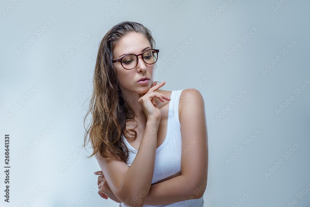 Close up portrait of beautiful young woman in stylish glasses and white shirt is posing elegantly isolated on gray background in a studio. Fashion shooting for accessories with female model Close up portrait of beautiful young woman in stylish glasses and white shirt is posing elegantly isolated on gray background in a studio. Fashion shooting for accessories with female model