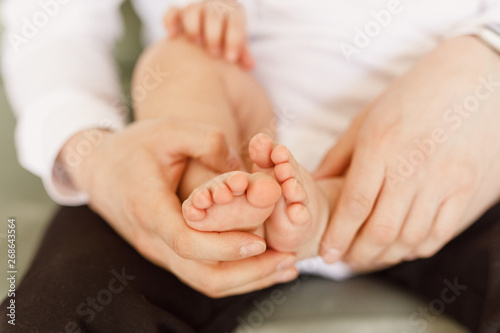 young man holds baby legs © Alexander