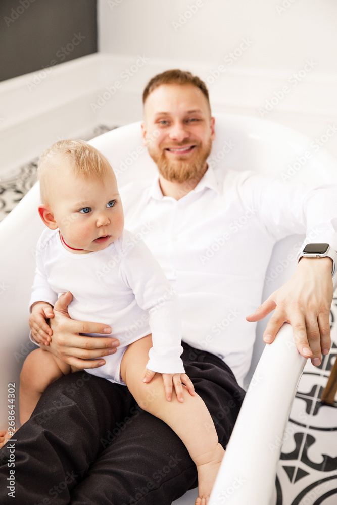 Fototapeta premium dad with a child sitting in the bathroom