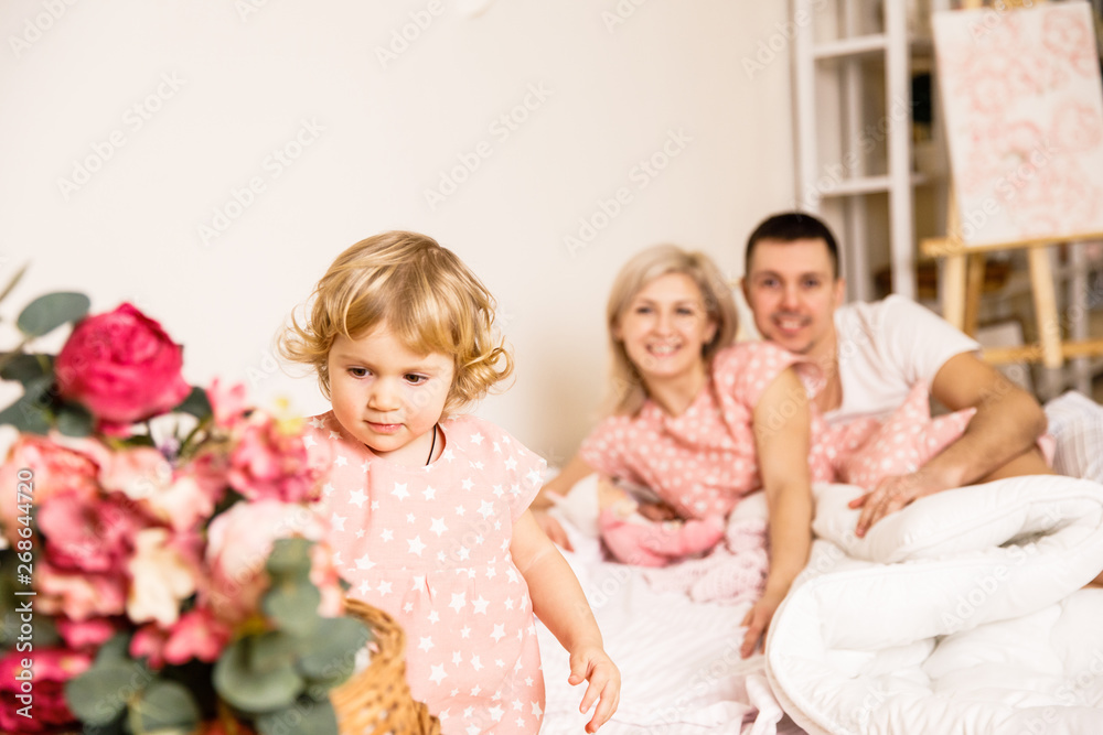 beautiful family dad mom and daughter in pajamas having fun in the bedroom on the bed in a bright apartment beautiful family dad mom and daughter in pajamas having fun in the bedroom on the bed in a bright apartment