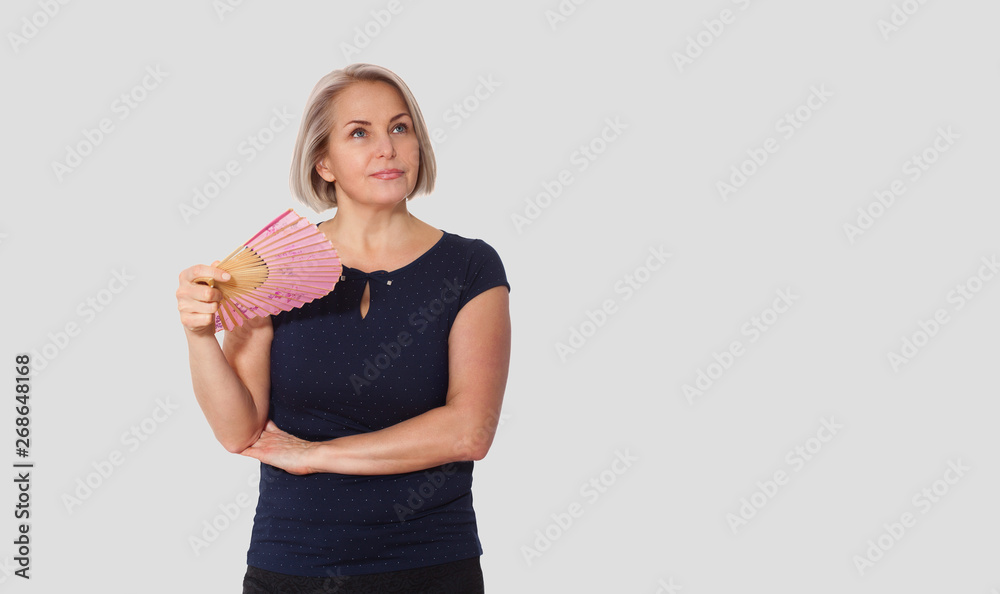 Attractive middle aged woman relaxing with fan. Mature woman experiencing hot flush from menopause Attractive middle aged woman relaxing with fan. Mature woman experiencing hot flush from menopause