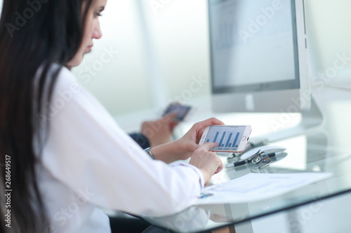 close up.the businesswoman uses her smartphone to work with financial data.