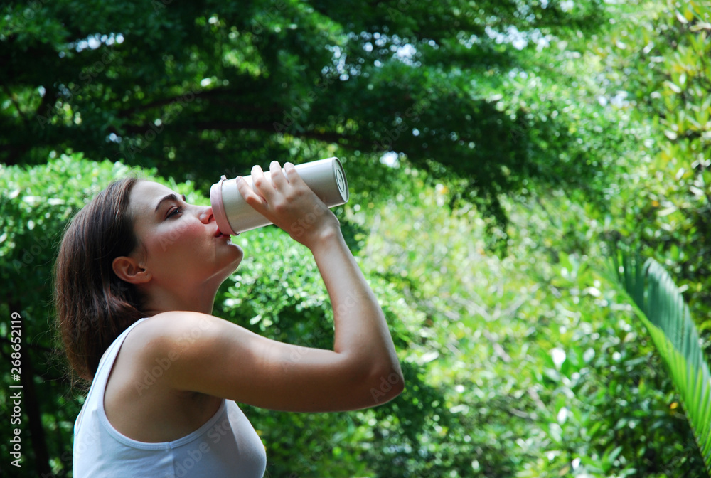 The young woman drinking water in the public park. The young woman drinking water in the public park.