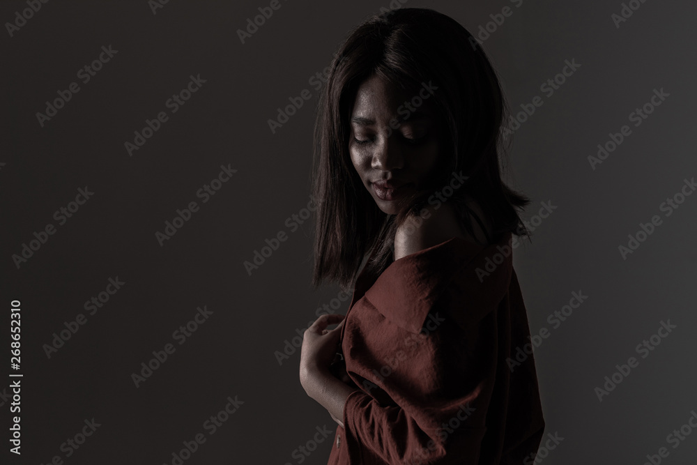 Portrait of a beautiful natural young African woman possing over black background