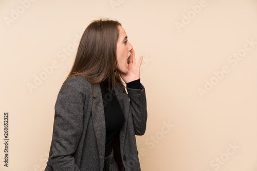 Young woman over isolated wall shouting with mouth wide open