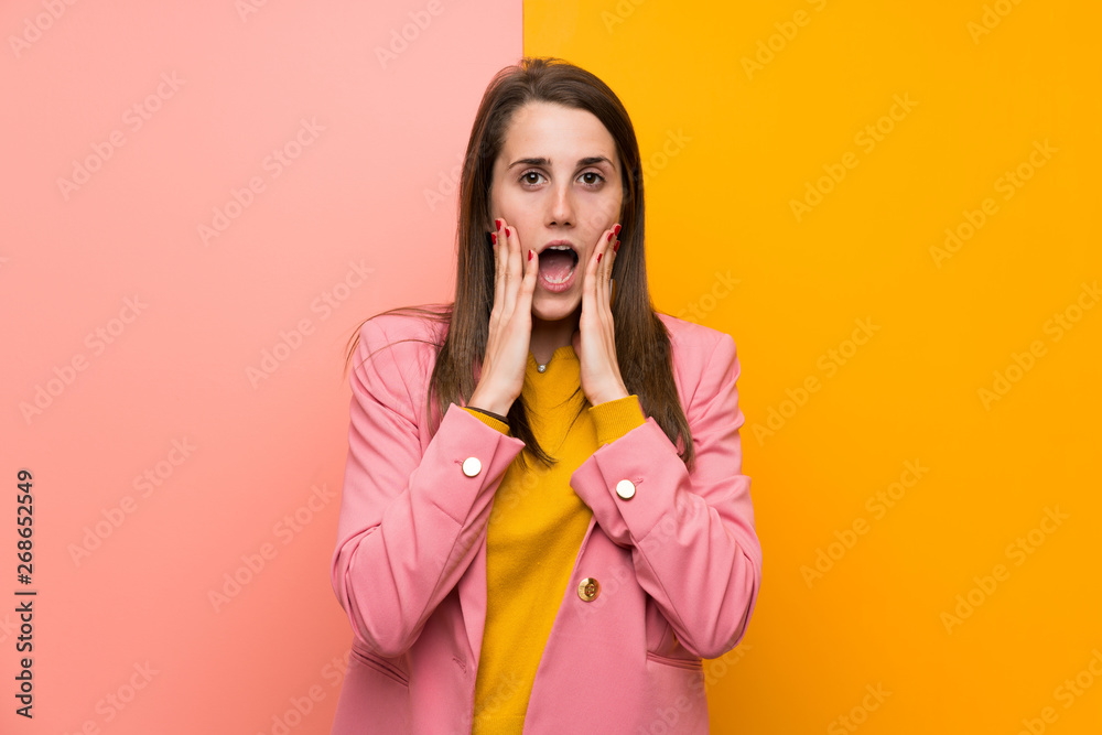 Young woman with pink suit over colorful background with surprise facial expression Young woman with pink suit over colorful background with surprise facial expression