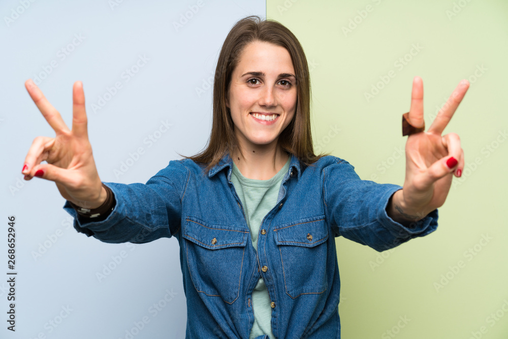 Young woman over colorful background smiling and showing victory sign Young woman over colorful background smiling and showing victory sign