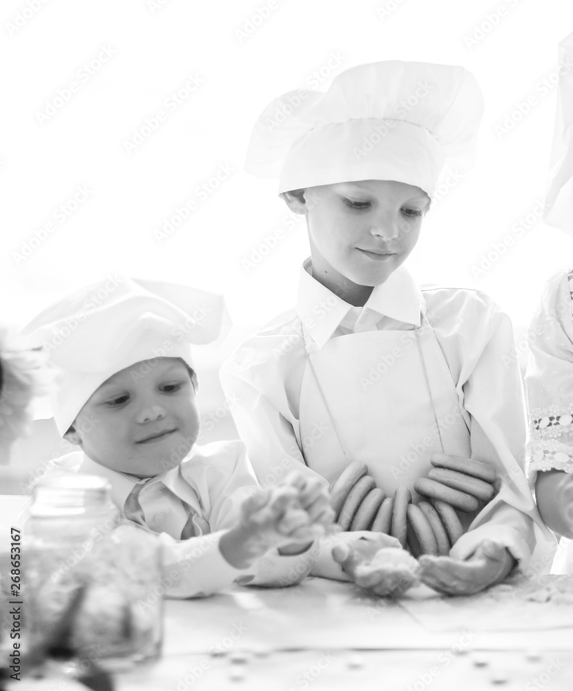 three happy baby cooks standing near the kitchen table three happy baby cooks standing near the kitchen table
