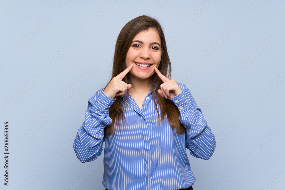 Young girl over isolated blue wall smiling with a happy and pleasant expression Young girl over isolated blue wall smiling with a happy and pleasant expression