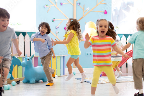 Group of happy children of boys and girls run in day care. Kids playing in kindergarten