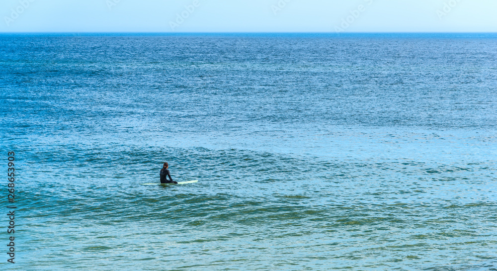 Surfer sitting on his surfboard waiting for the waves in Florida