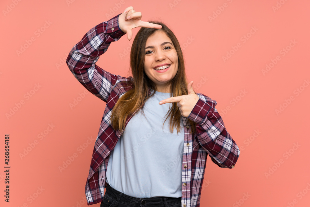 Young girl over pink wall focusing face. Framing symbol Young girl over pink wall focusing face. Framing symbol
