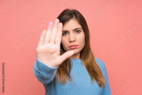Young girl with blue sweater making stop gesture with her hand