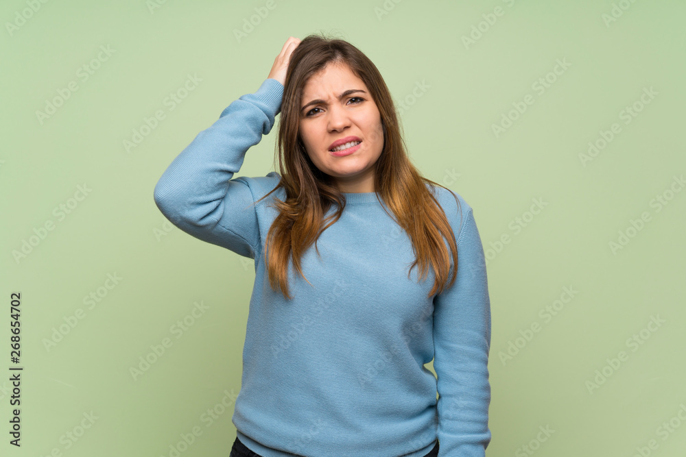 Young girl over green wall with an expression of frustration and not understanding Young girl over green wall with an expression of frustration and not understanding